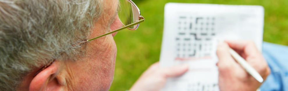 senior man doing crossword in garden